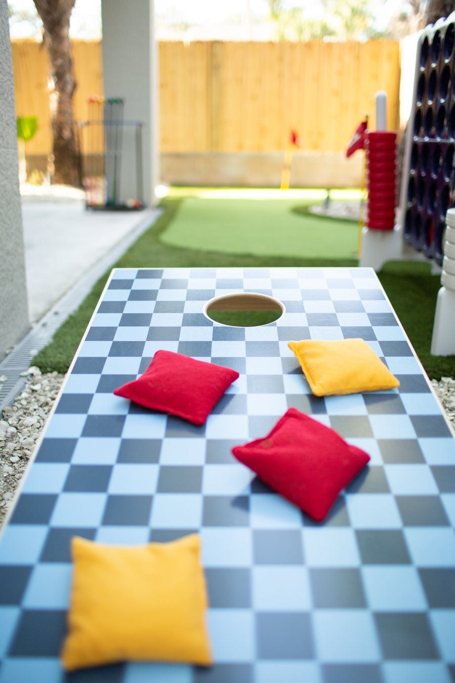 Checkered cornhole board with red and yellow bean bags