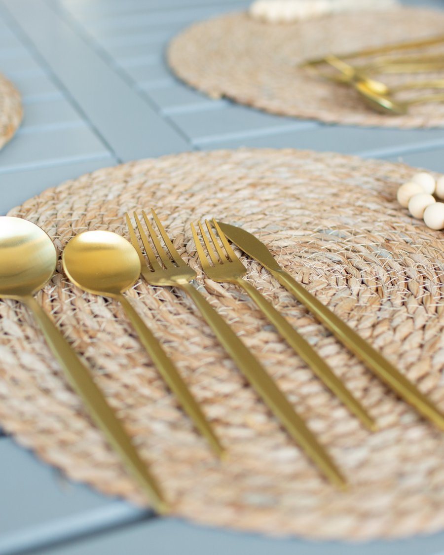 Gold flatware on woven placemats at the outdoor dining table