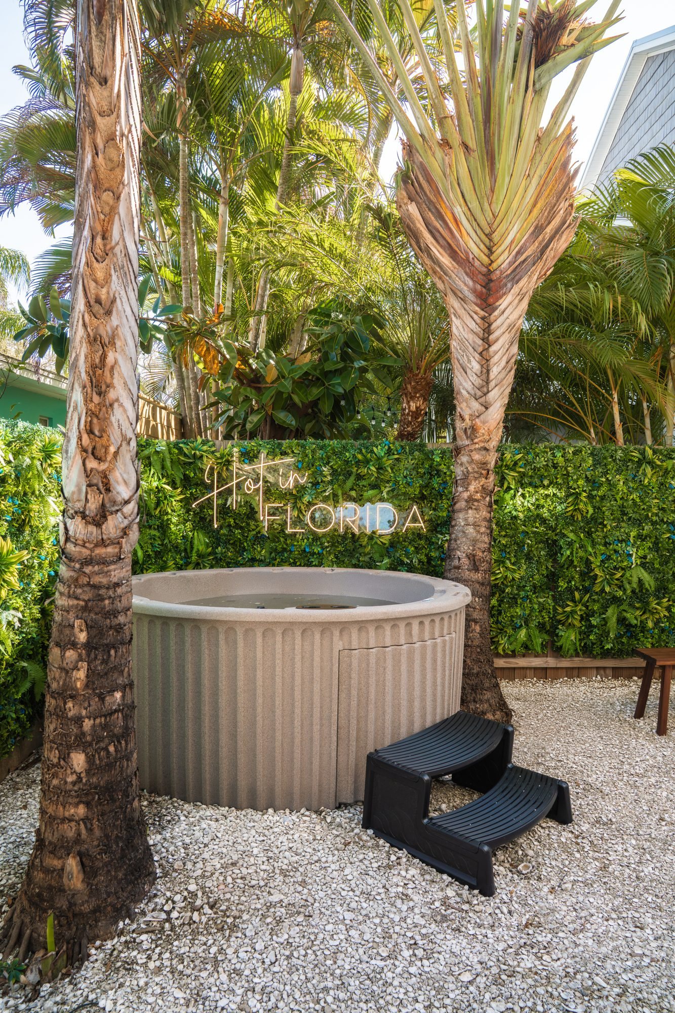 Private hot tub under palm trees with a Hot in Florida neon sign