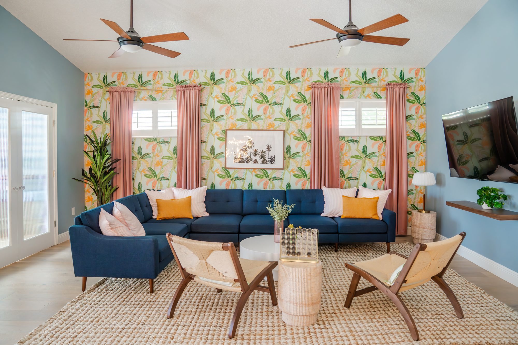 Living room with navy sectional and tropical wallpaper