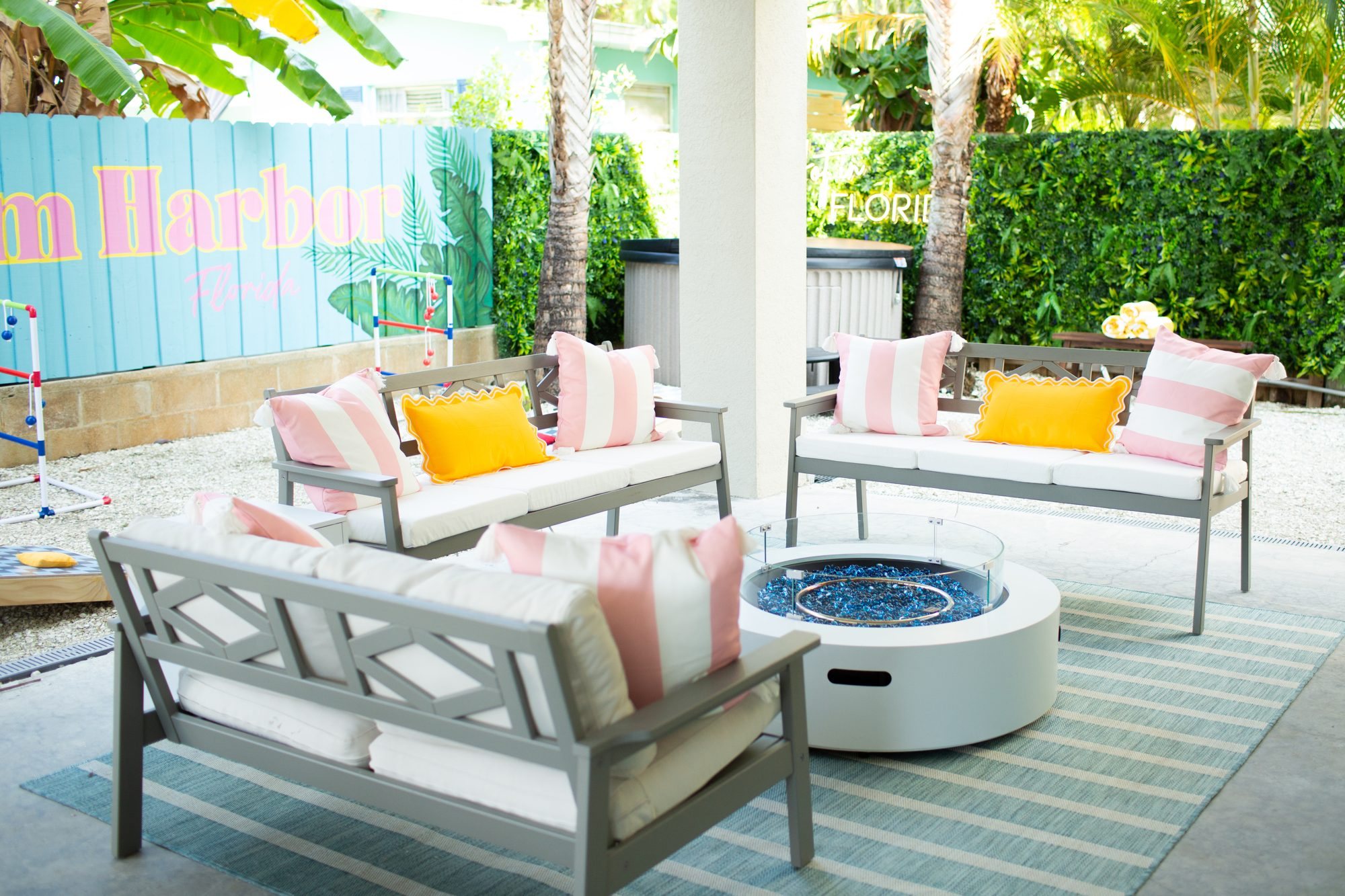 Back patio with fire pit, pink and yellow pillows and the Palm Harbor mural