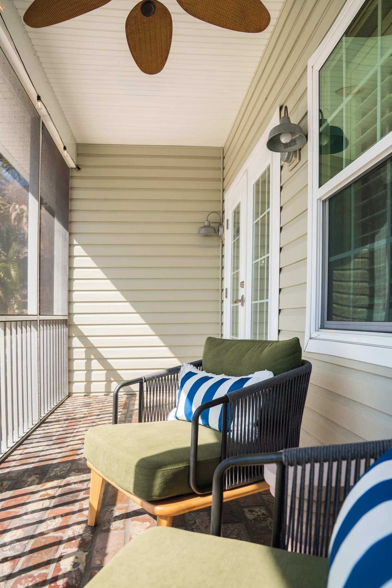 Screened front porch with two cushioned chairs and a ceiling fan