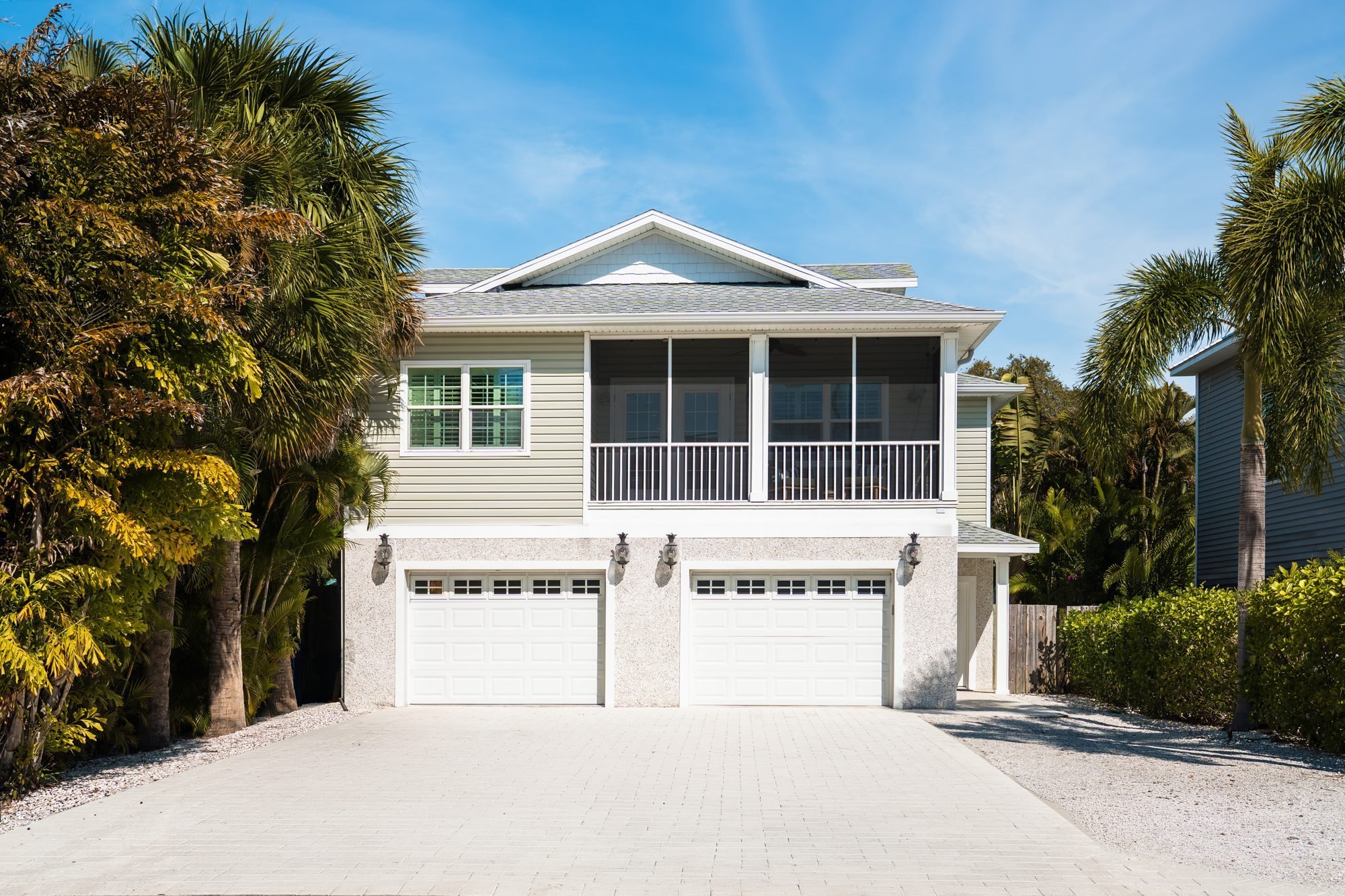 Front of the Bay Breezes house with palm trees and a two-car garage