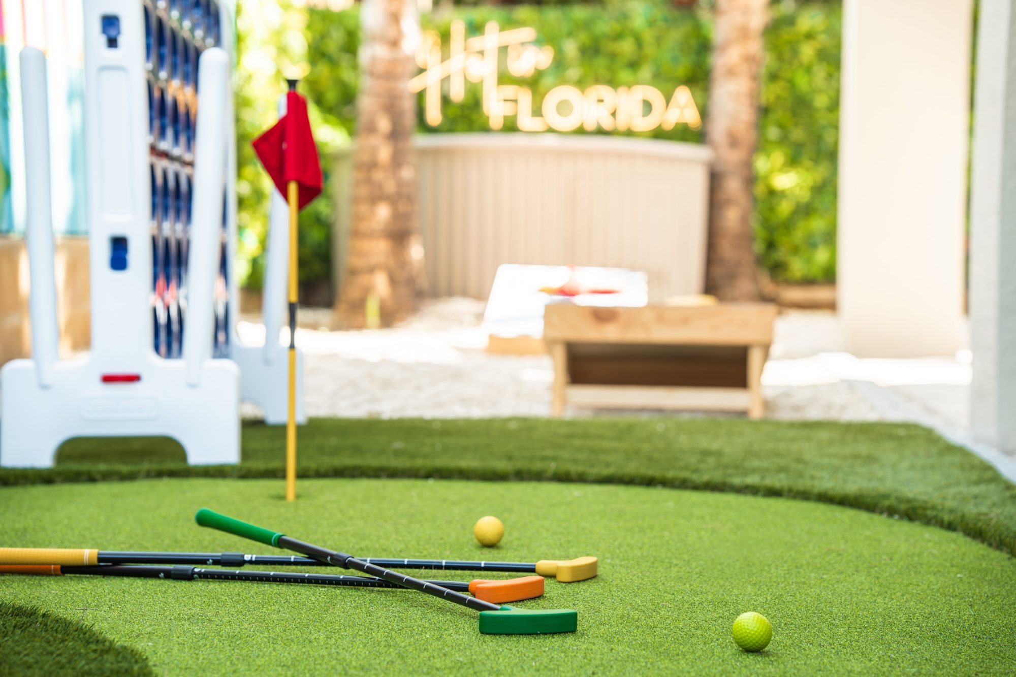 Backyard putting green with colorful putters, cornhole and the Hot in Florida sign