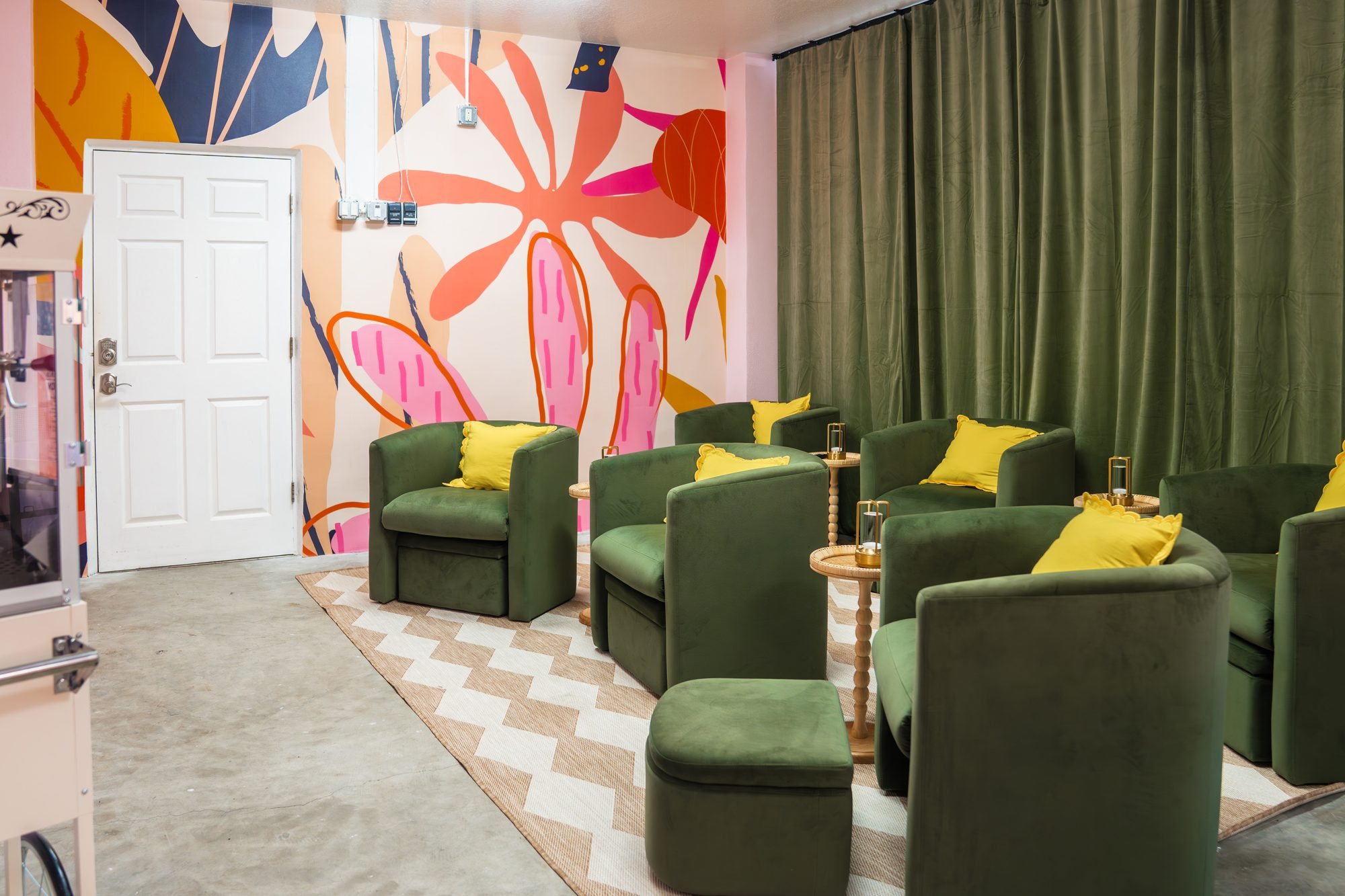 Movie room with green velvet chairs, yellow pillows and a colorful floral mural